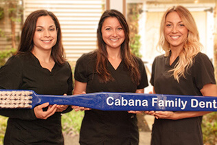 Three team members holding giant toothbrush